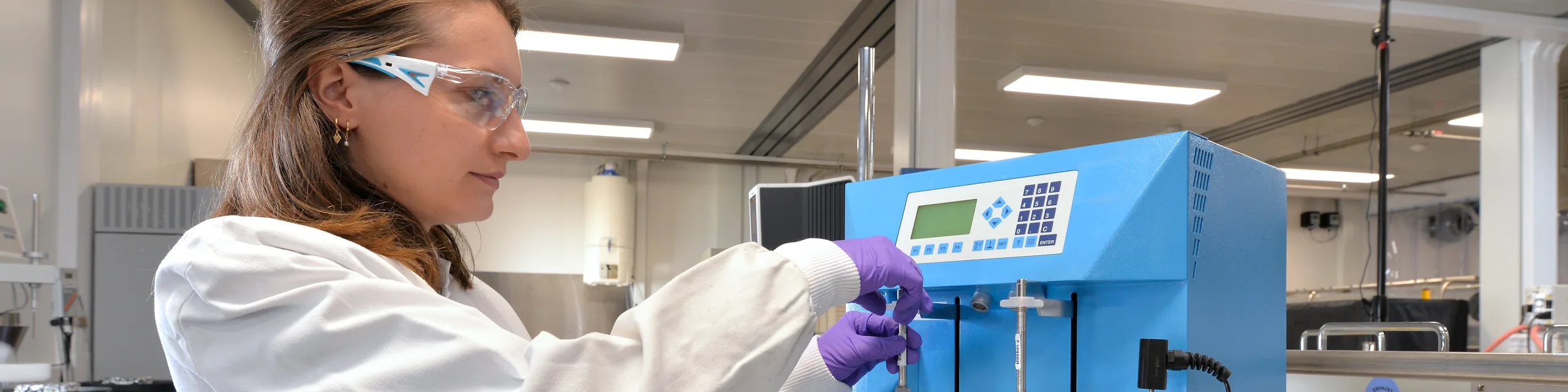 female lab technician looking through microscope